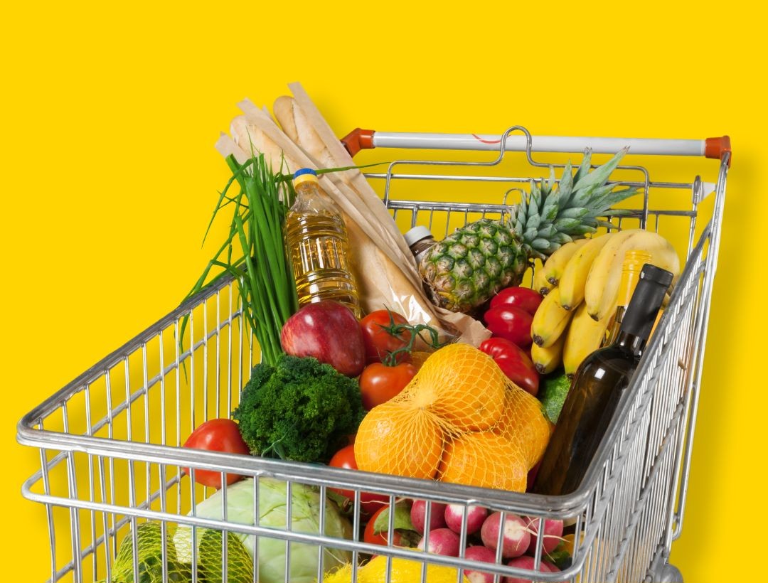 A shopping cart filled with fruits and vegetables.