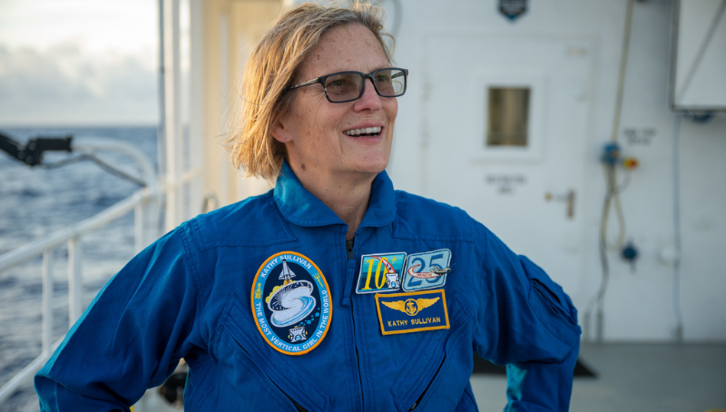 Astronaut and oceanographer Dr. Kathryn Sullivan stands aboard a ship smiling following her visit to the Challenger Deep, the deepest known part of the ocean.  