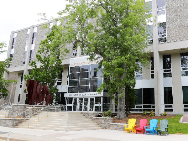 The entrance to the Weldon Law Building in summer with trees and colourful chairs out front. 
