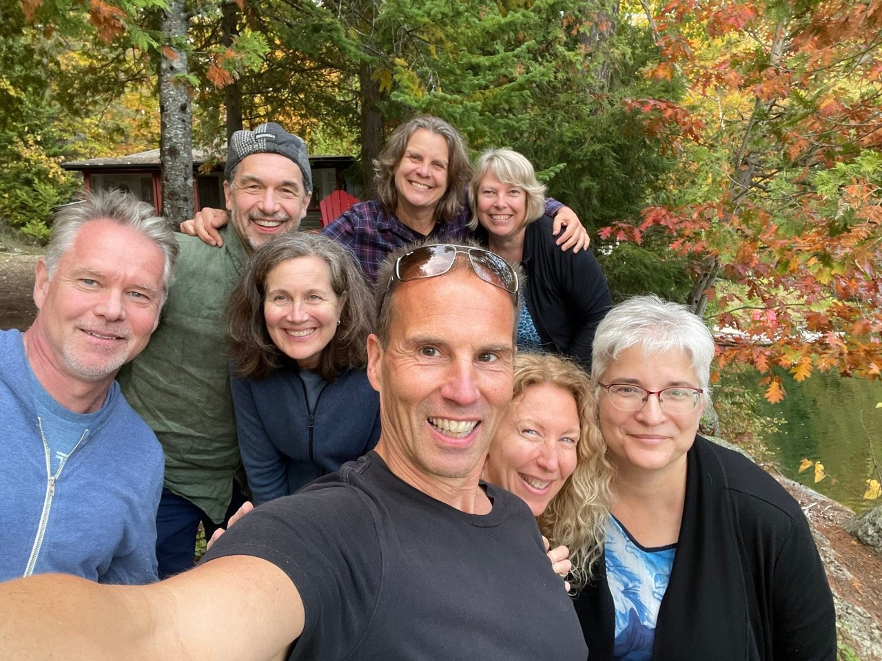 A small group of men and women smiling together in a rustic outdoor setting.