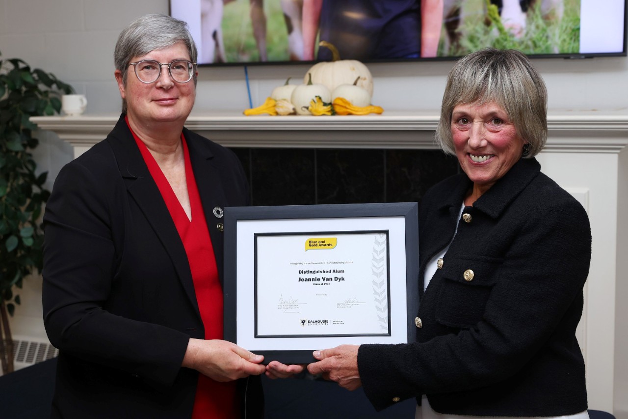 Two women smiling at an event holding a framed certificate between them.