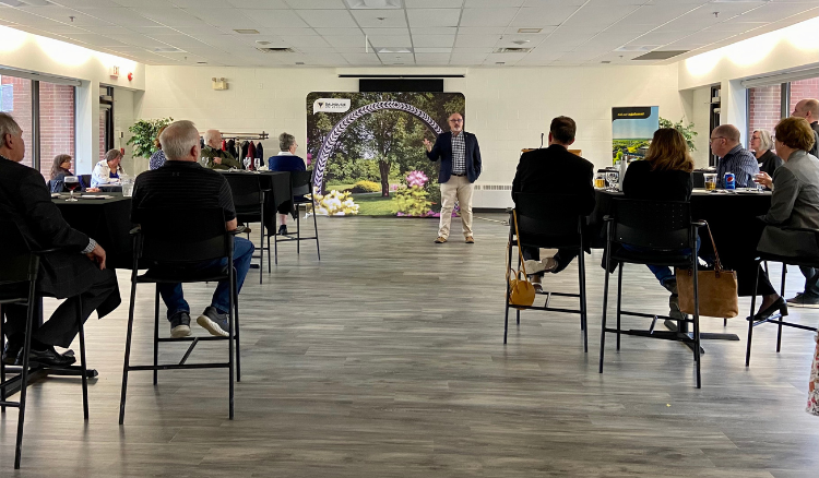 People are seated at cruiser tables while listening to a presenter at the front of the room.