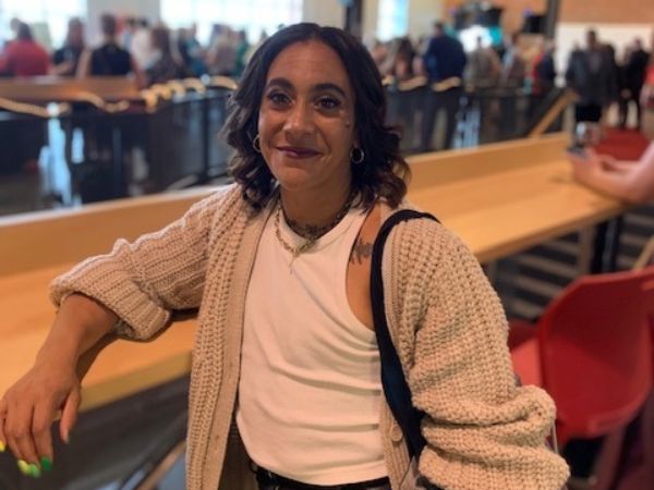 A woman leaning on a high countertop, smiing, with a crowd in the background behind.
