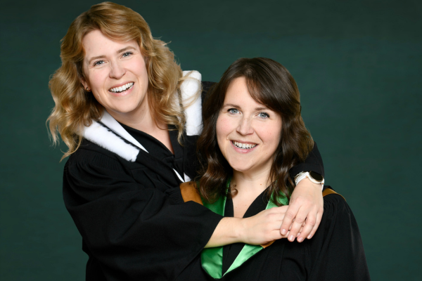 A portrait of Courtney and Meghan Bragg embracing in graduation gowns.
