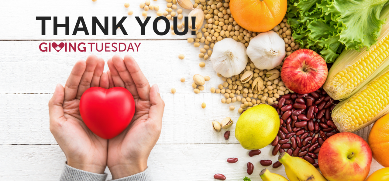 A red heart object lies in the palms of two hands with a collection of fresh food in the background.
