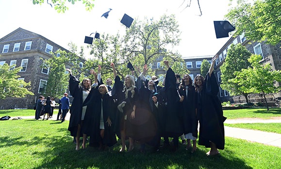 A group of graduates in their gowns throwing their hats in the air.