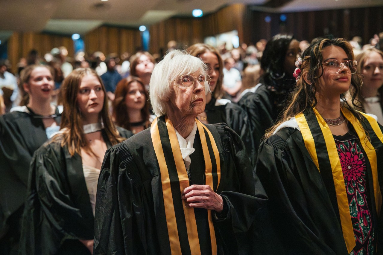 Diverse group of graduands standing during convocation ceremony.