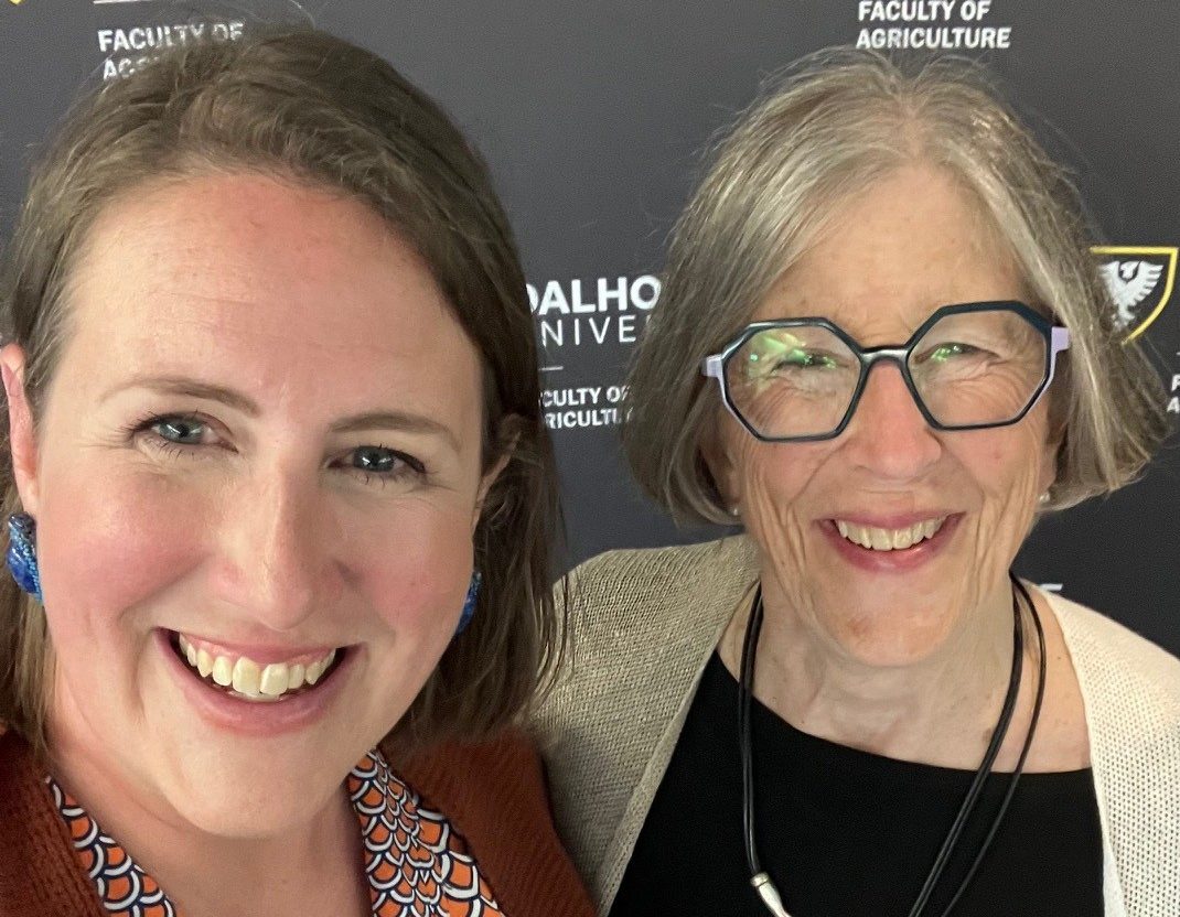 Daughter and mother smiling in a selfie with branded backdrop.
