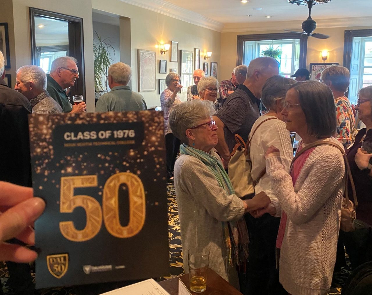 People mingling at a restaurant during a 50th reunion gathering.