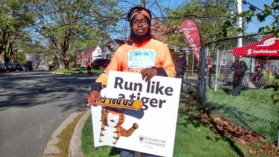 Rahman holds a sign along the path of the Bluenose Marathon in Halifax,