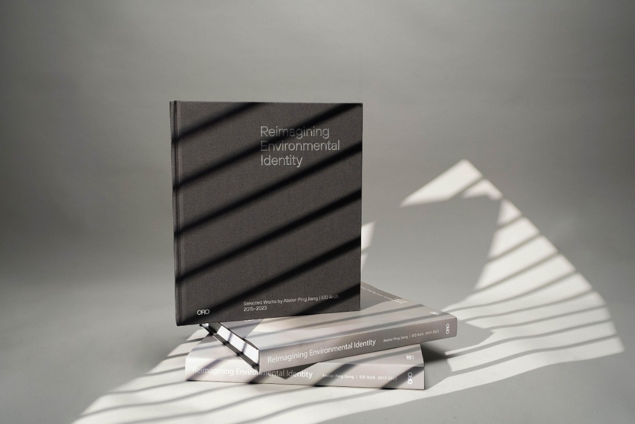 Two books stacked with one more perched on top with a plain cover, shone in a light with a lined shadow.