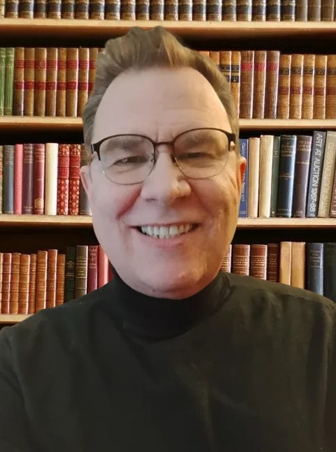 Roger Thompson portrait with bookshelf background.