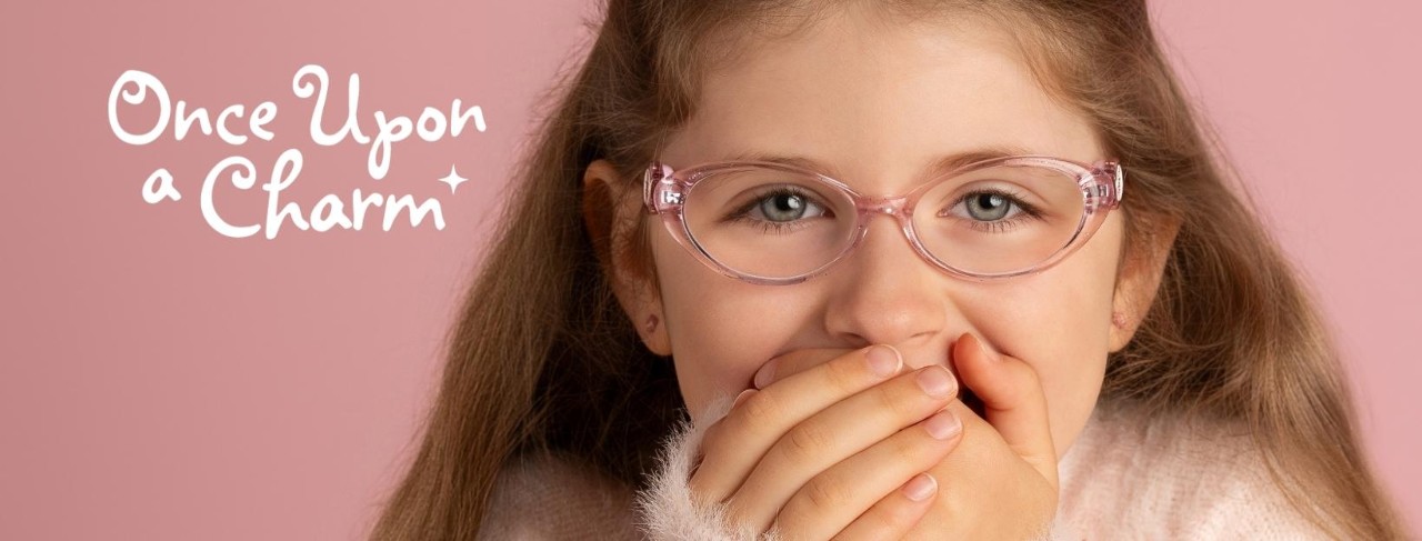 A girl wearing eye glasses covers her smile with her hands. 