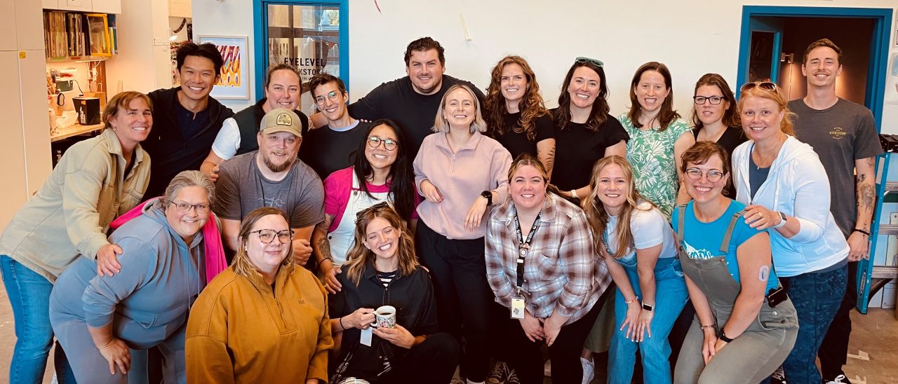 A large group of people dressed casually pose indoors.