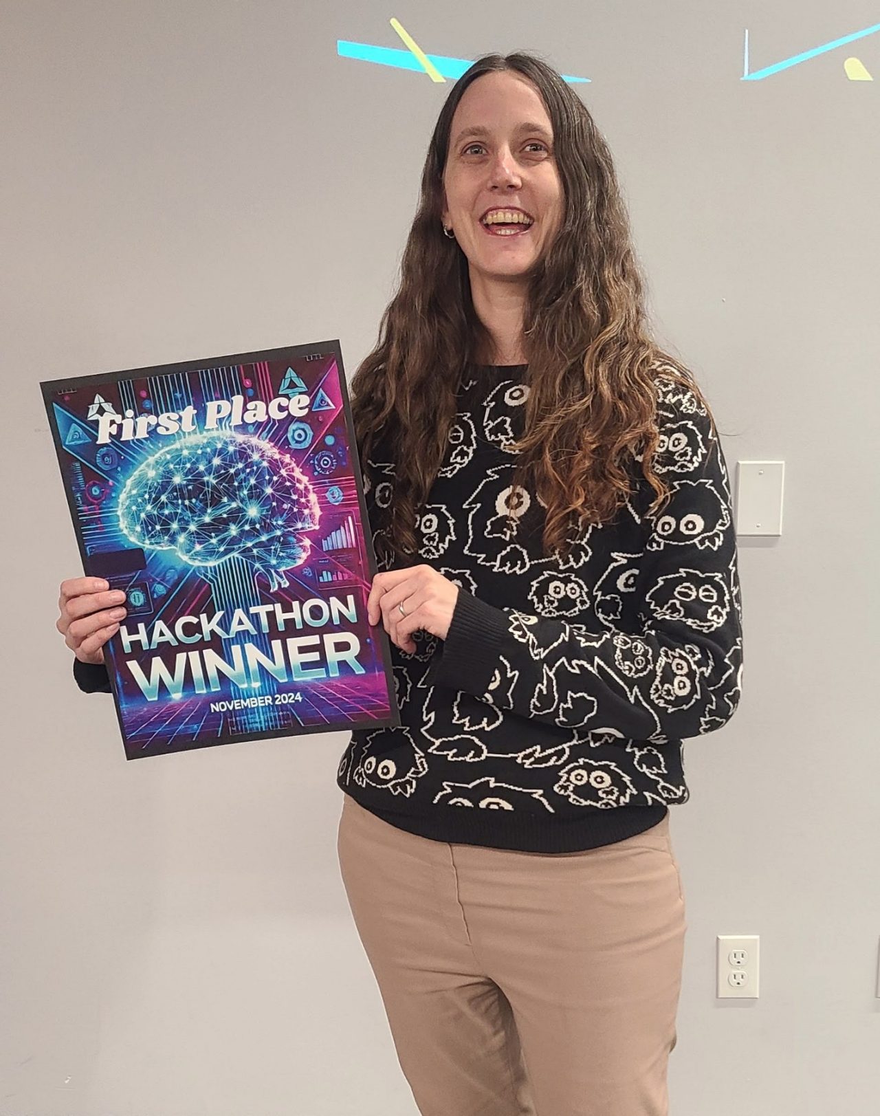 Parker smiling broadly holding a plaque commemorating her Hackathon win at the event.