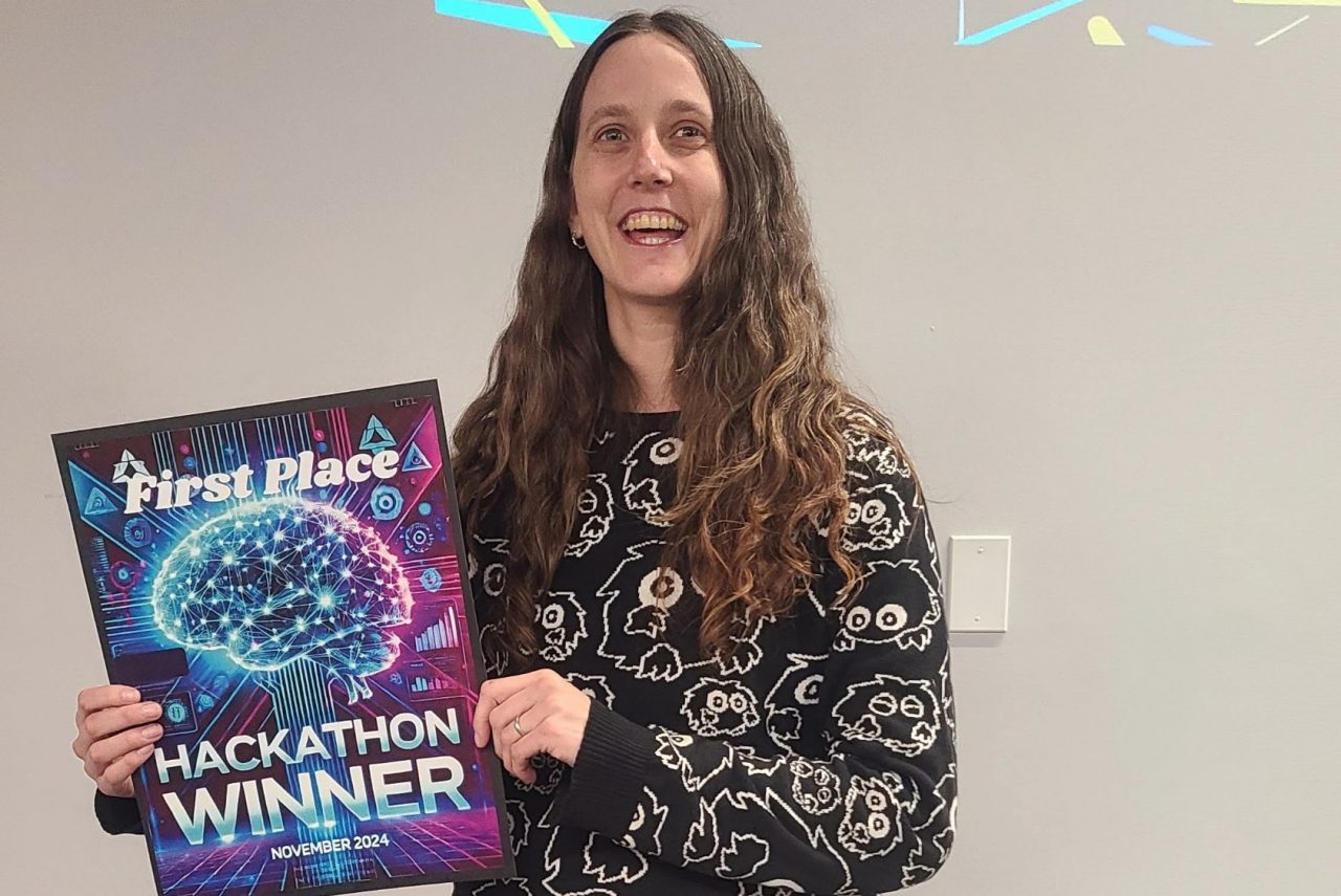 Parker smiling broadly holding a plaque commemorating her Hackathon win at the event.
