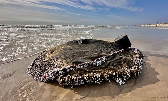 A tuna fishing net is shown washed up on a beach shore.