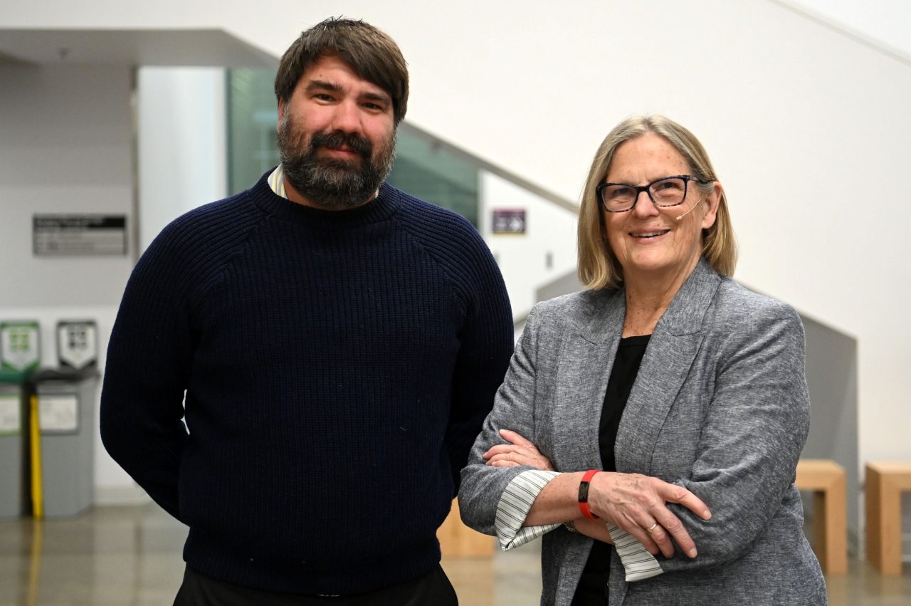 David Barclay stands with his arms behind his back next to Kathryn Sullivan with her arms crossed in front at the event.