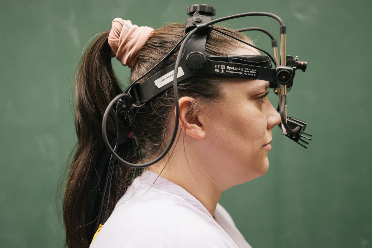 A woman in profile with hair in a scrunchie and a device fitted around her head and in front of her eyes.