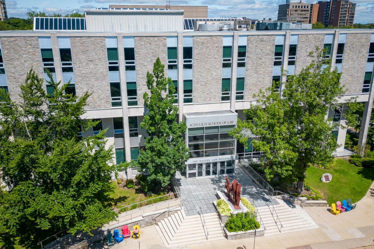 An aerial view of the entrance to the Weldon Law building in fine weather with greenery surrounding and colourful chairs out front.