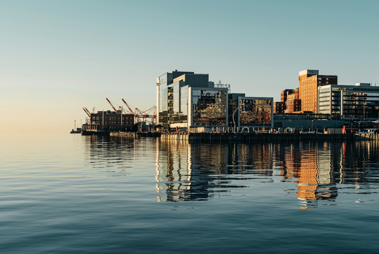 A morning photo of the Halifax waterfront from the harbour with still water.