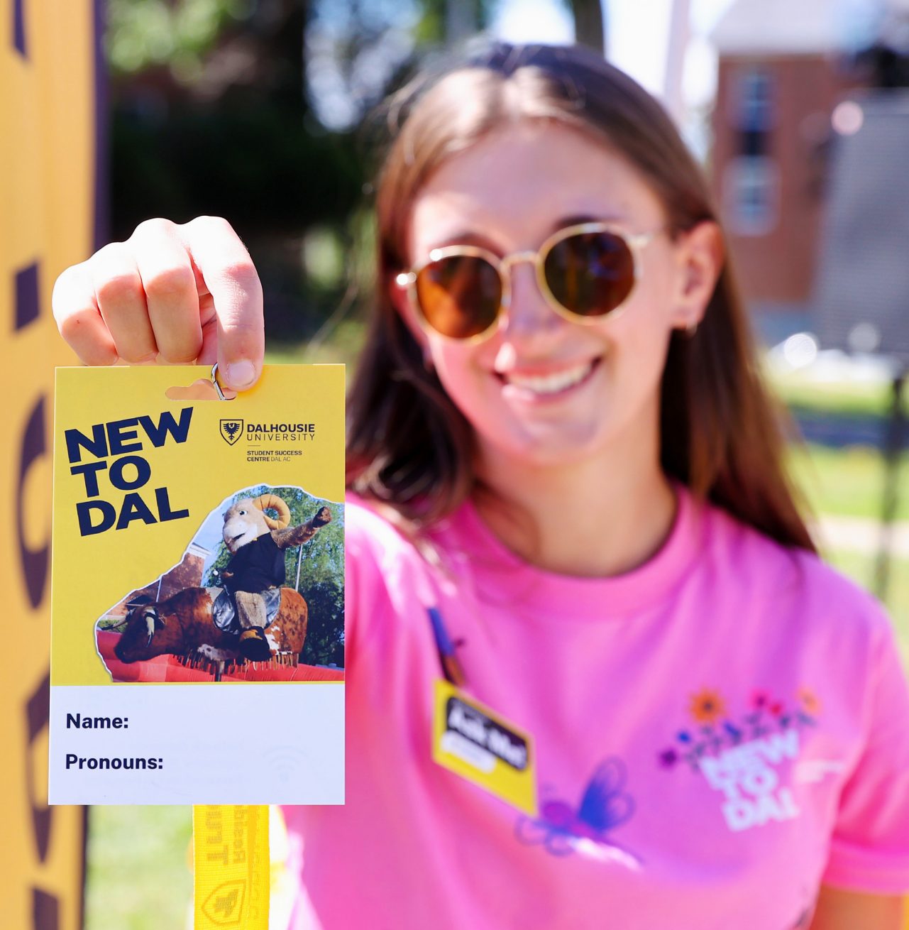 volunteer holds up New to Dal badge