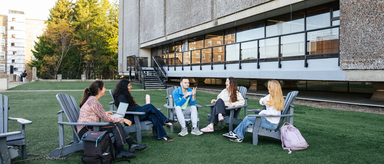 Group of students sitting outside the Killiam library in chairs talking
