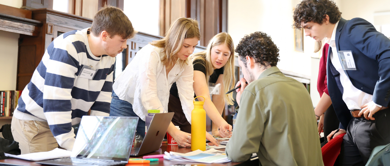 Group of students working together with laptops around a table