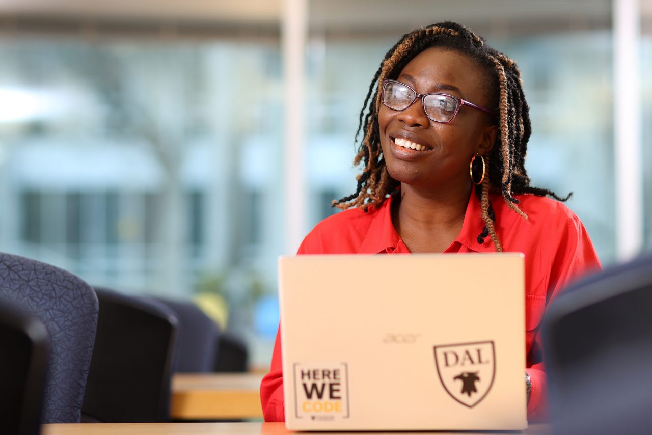 woman in red shirt with open laptop smiling