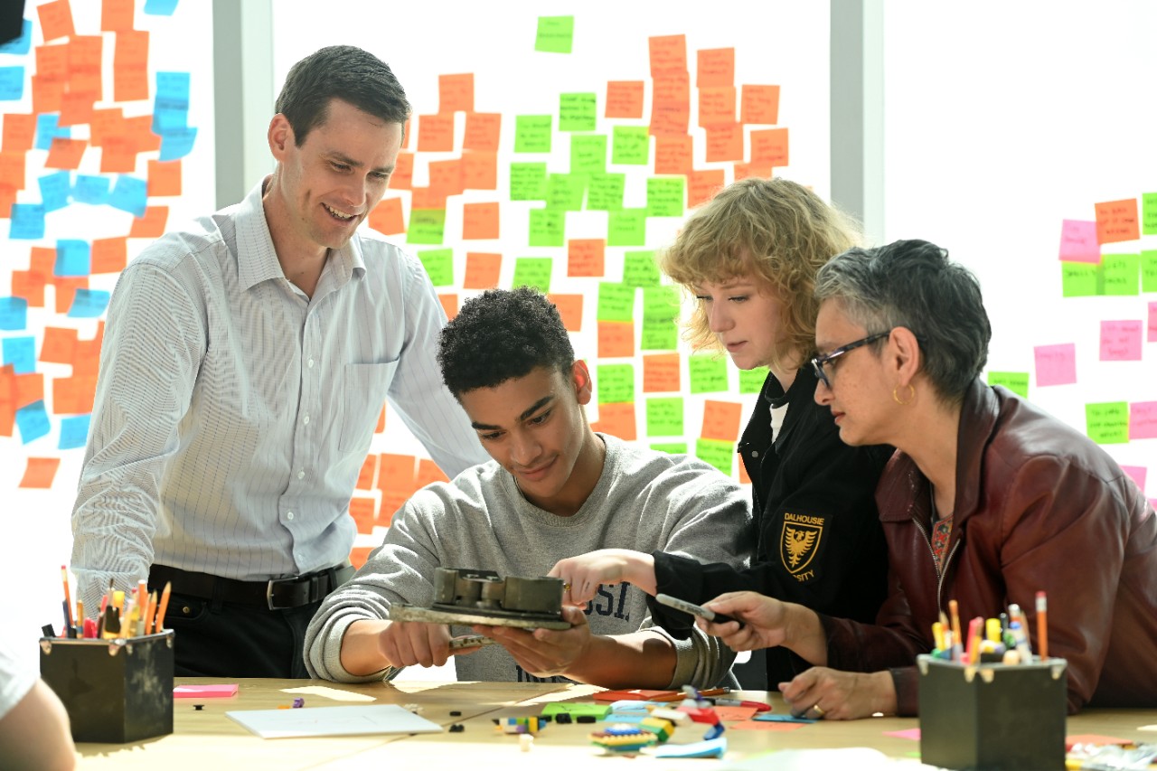 4 people huddle around device working together