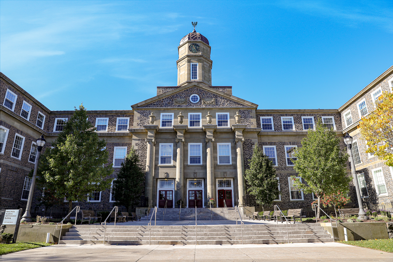 A photo of the Henry Hicks Building in a bright day with an almost clear blue sky with the clock tower in the center of the image.