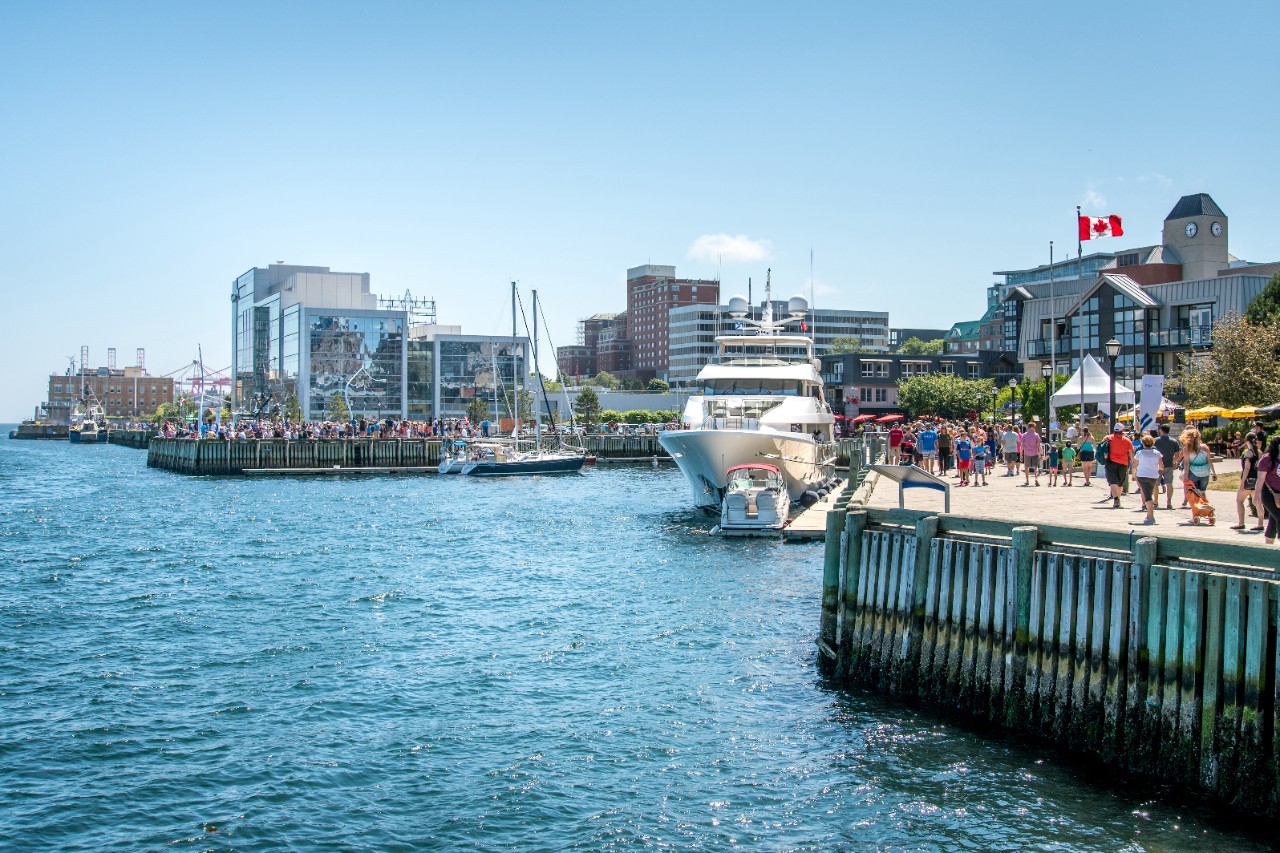 The Halifax Waterfront with a view of the harbour, the ferry, and the waterfront building skyline in the background.
