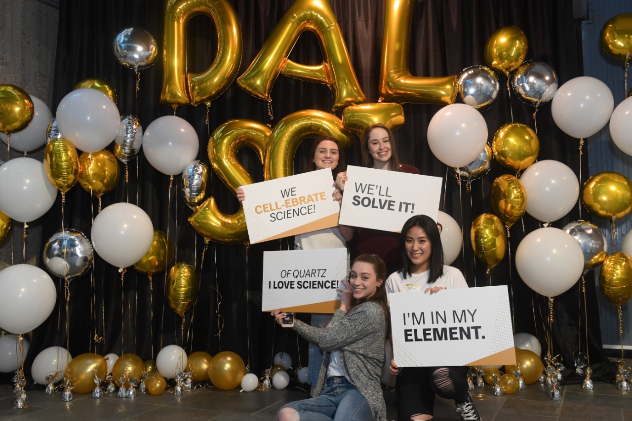 Students hold signs and pose for a photo while they attend the Dalhousie Science Deans Reception