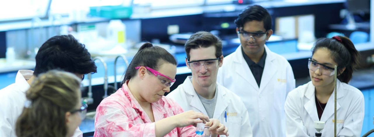 Undergraduate science students gather around an instructor during an experiment in the Dalhousie Chemistry lab