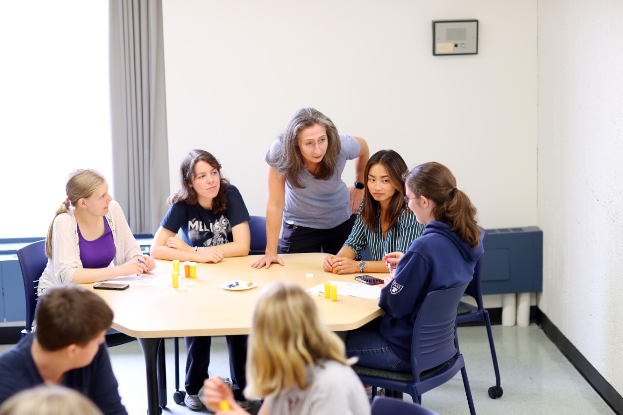 Students and faculty sit at a table in a classroom while they run a psychology experiment