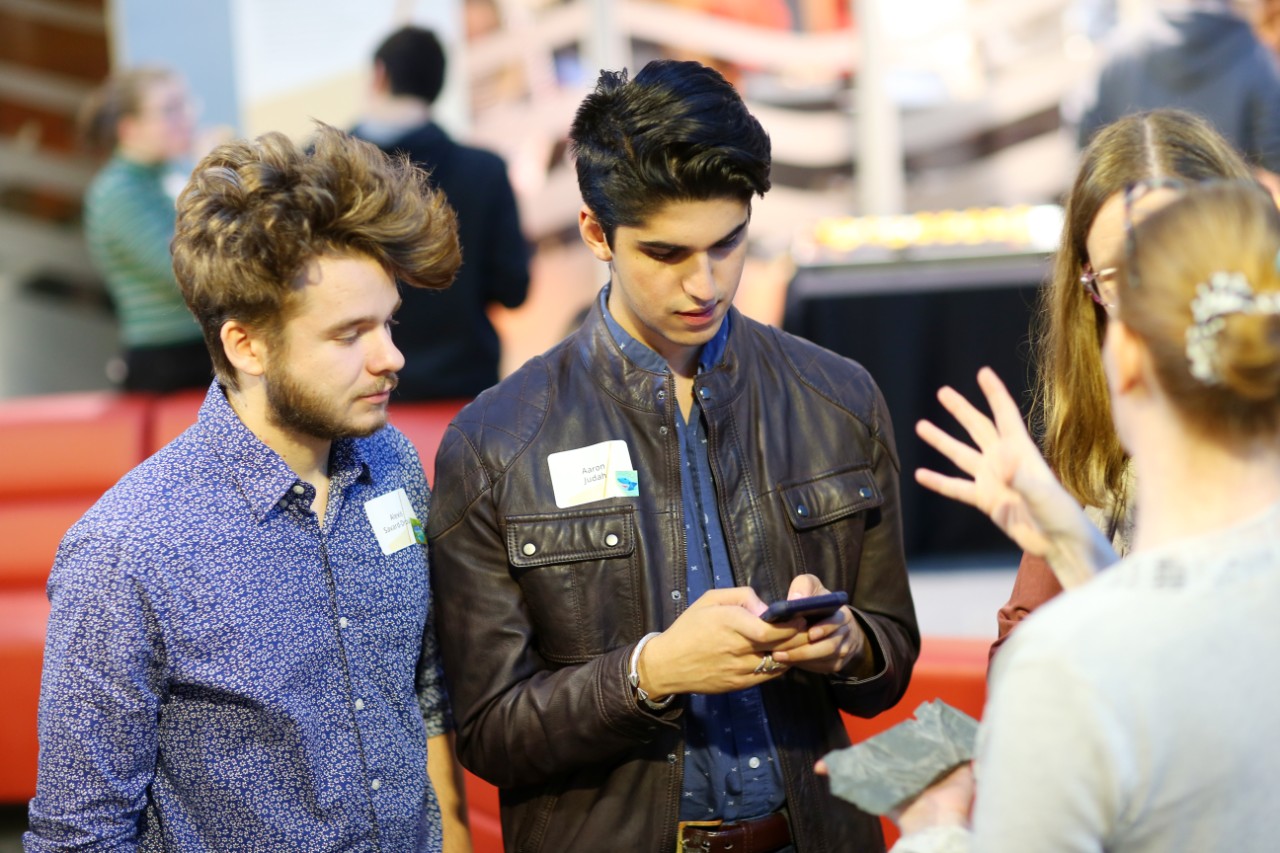 Students and faculty talk together and look at a phone while they attend the Dalhousie Science Deans Reception