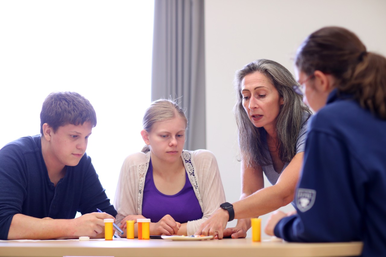 Students and faculty sit together at a table during a psychology class