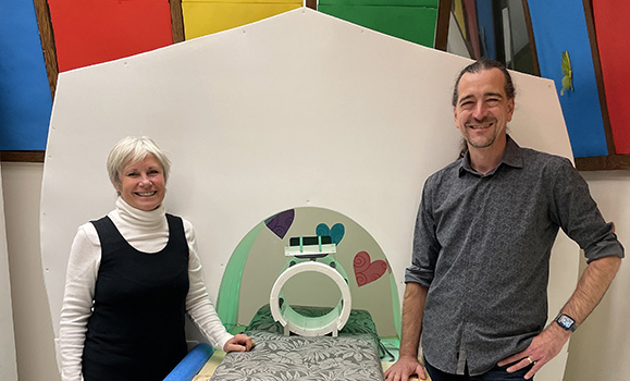 Two lab members stand beside a mock MRI machine 