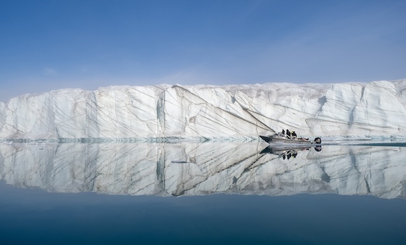 A small boat sails past a stretch of glaciers in the Canadian Arctic