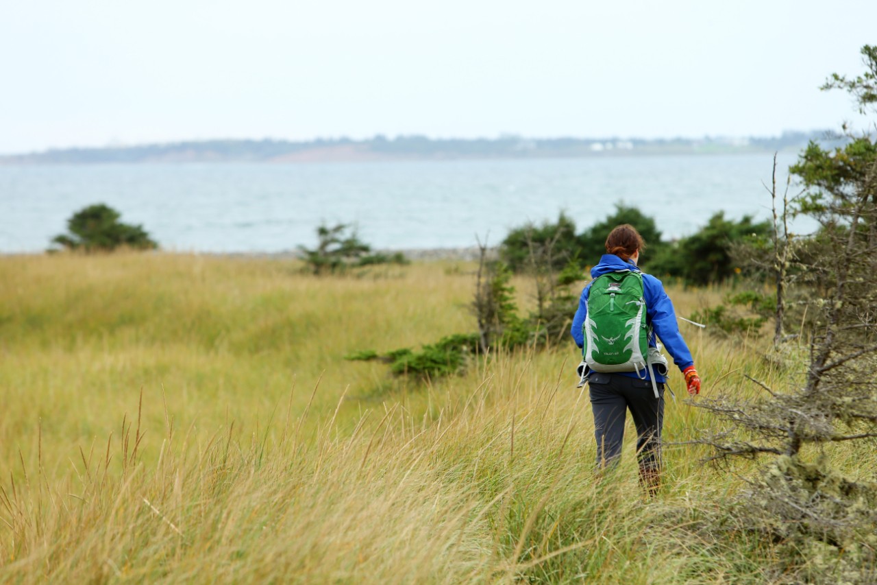 A student walks through the grass while they attend a field trip at Conrad's Beach, Nova Scotia