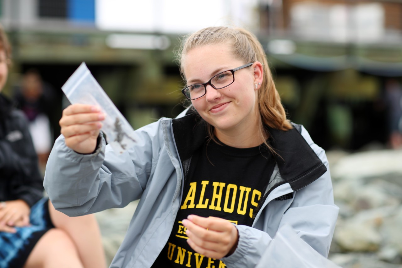 Dalhousie Science student holds up a sample in a clear bag while on a field trip in Halifax Canada
