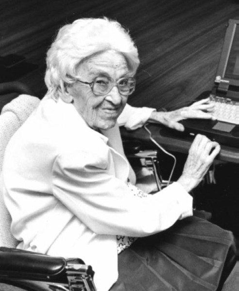 A black and white photo of an older woman seated at a desk