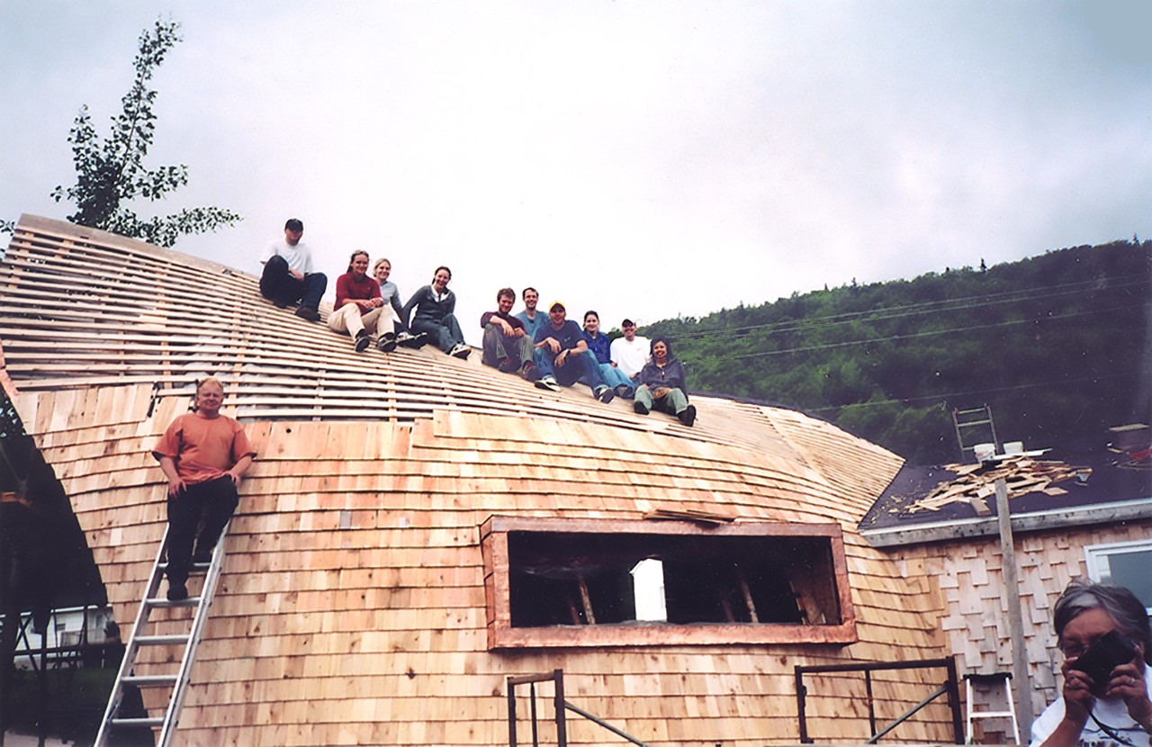 A group of people seated on a wooden structure that is under construction