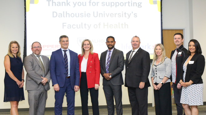 A group of people standing in front of a screen that reads Thank you for supporting Dalhousie University's Faculty of Health