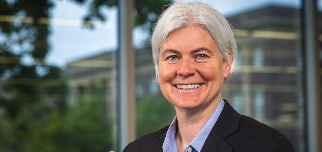 A woman wearing a blazer and blue shirt in front of a window