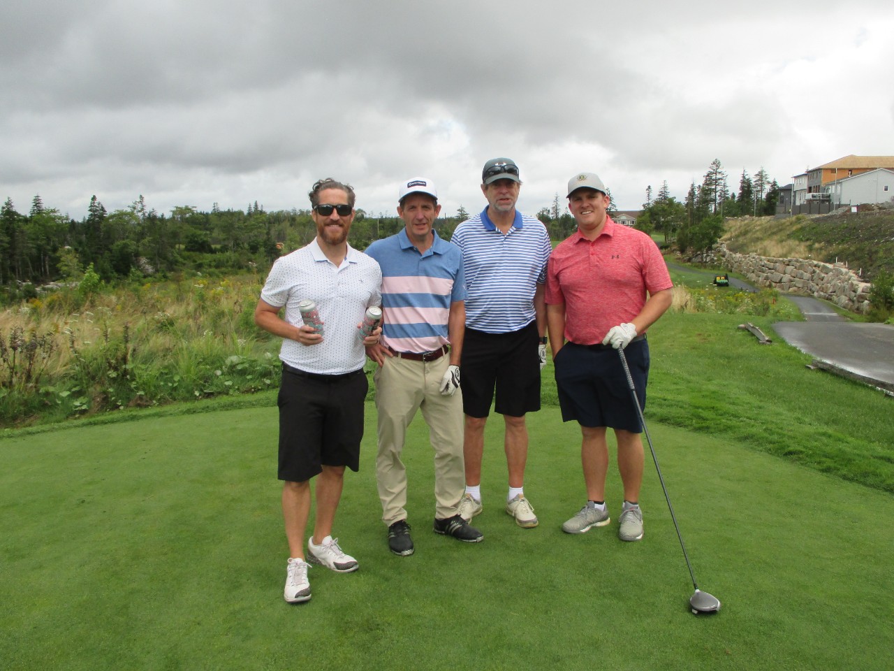 Four men standing on a tee box at a golf course
