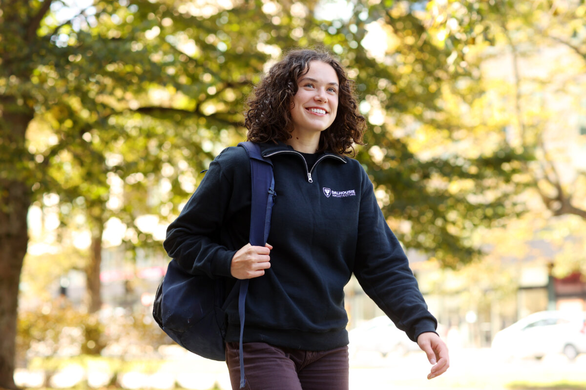 A woman wearing a blue sweater and backpack walking outside