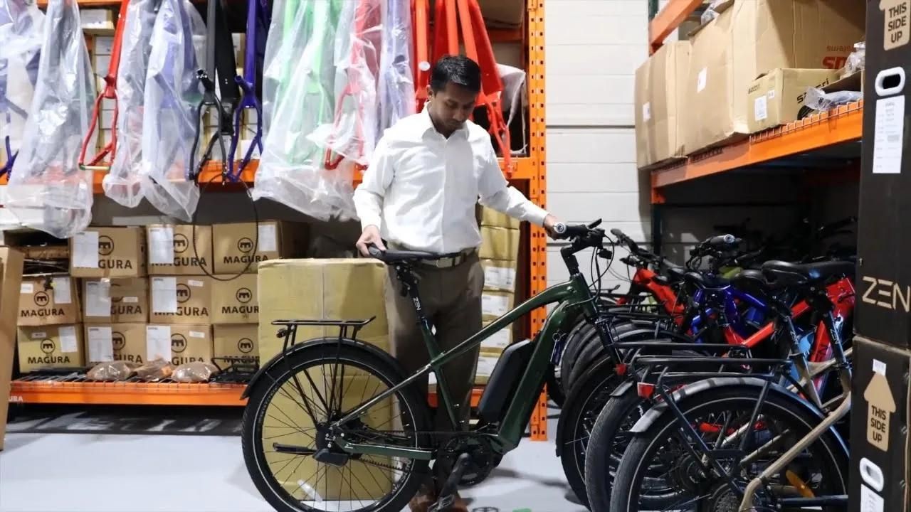 Kempaiah is standing with a rack of bikes inside a warehouse.