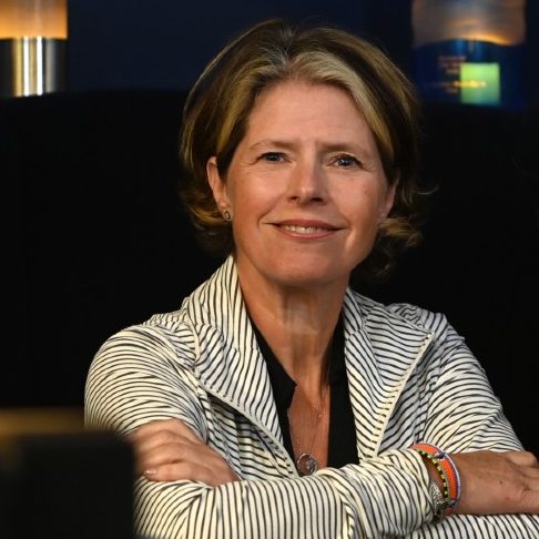 Lisa Murphy seated with arms crossed in a restaurant, smiling.