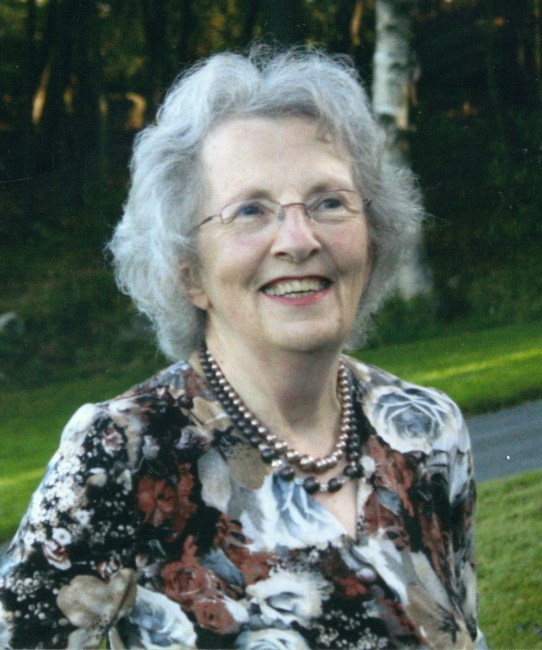 A woman wearing a floral blouse poses outside